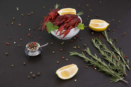 Delicious boiled crayfish close-up on a stone plate with pepper, lemon and parsley. free space for your text. Black background.の写真素材