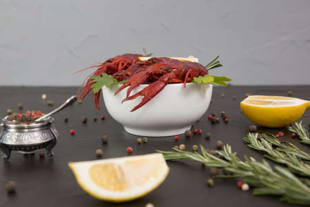 Delicious boiled crayfish close-up on a stone plate with pepper, lemon and parsley. free space for your text. Black background.の写真素材