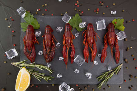 Delicious boiled crayfish close-up on a stone plate with lemon and parsley.の写真素材