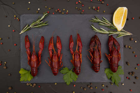Delicious boiled crayfish close-up on a stone plate with lemon and parsley.の写真素材