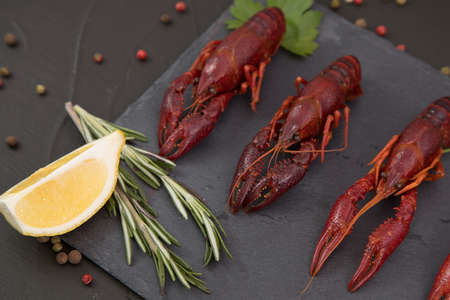 Delicious boiled crayfish close-up on a stone plate with lemon and parsley.の写真素材
