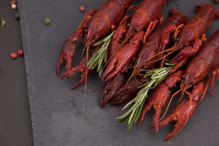 Delicious boiled crayfish close-up on a stone plate with pepper, lemon and parsley.の写真素材