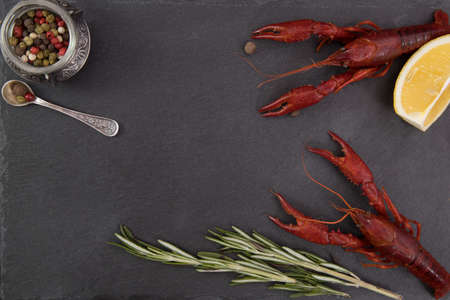 Delicious boiled crayfish close-up on a stone plate with pepper, lemon and parsley.の写真素材