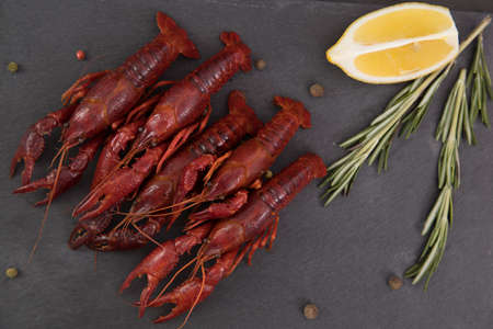 Delicious boiled crayfish close-up on a stone plate with pepper, lemon and parsley.の写真素材