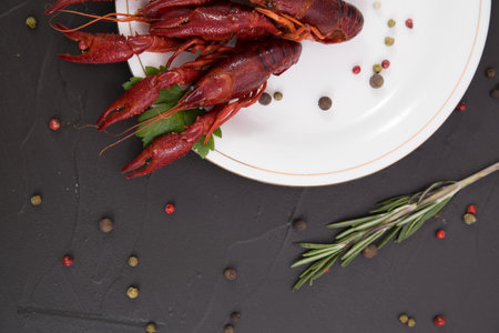 Delicious boiled crayfish close-up on a stone plate with pepper, lemon and parsley. free space for your text. Black background.の写真素材