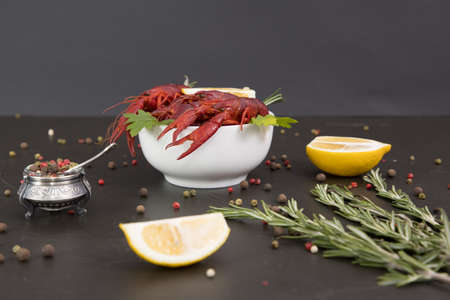 Delicious boiled crayfish close-up on a stone plate with pepper, lemon and parsley. free space for your text. Black background.の写真素材