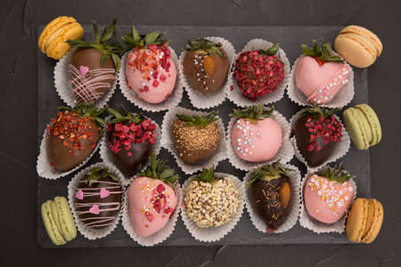 Assorted strawberries in chocolate with macaron, sweet dessert, free space for your text, sprinkled with nuts, top view, isolated background.の写真素材