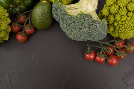 Healthy vegetarian food, fresh green food, green vegetable, romanesco broccoli, pepper, zucchini and avocado, free space in your text, on a black table.の写真素材