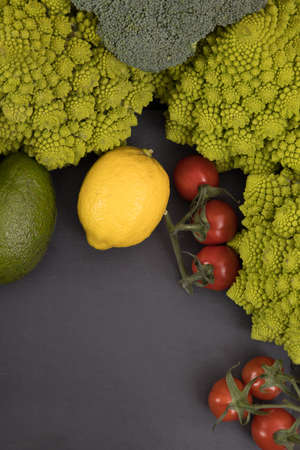 fresh vegetable, romanesco broccoli, pepper, zucchini, avocado, lemon and cherry tomato free space in you text, on a black table.の写真素材