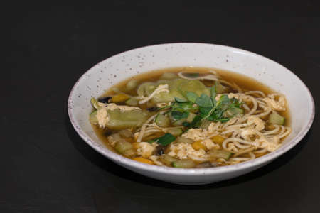 Hot soup with Coconut nut milk, chiken, pasta and vegetable on a black background.の写真素材