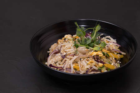 Plate of wok salad with vegetables, on a black background.の写真素材