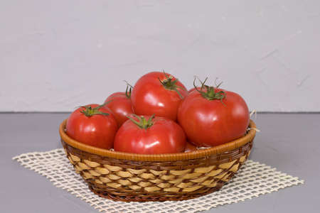 Red tomatoes in the basket, on gray background.の写真素材
