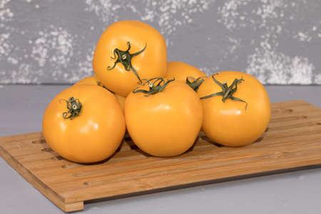 yellow tomatoes sliced, on brown wooden desk and gray background.の写真素材