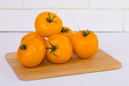 yellow tomatoes sliced, on brown wooden desk and white background.の写真素材