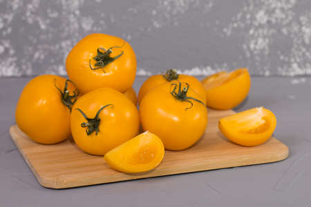 yellow tomatoes on brown wooden desk and gray background.の写真素材