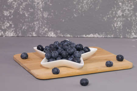 Fresh blueberry in court, on a wooden table and gray background.の写真素材