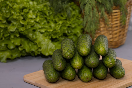 Fresh cucumbers with green salad, on wooden desk.の写真素材