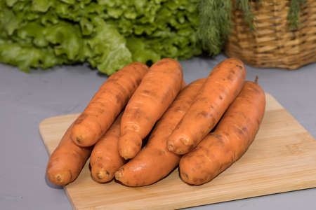 Carrots on wooden board with green salad.の写真素材