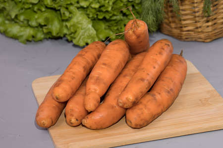 Carrots on wooden board with green salad.の写真素材