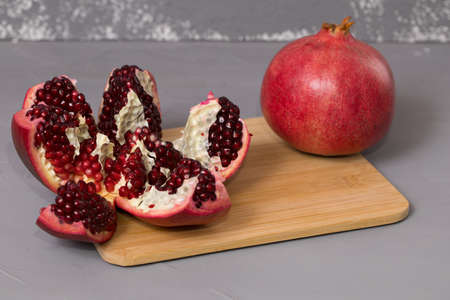 Open frash pomegranate on a wooden desk, pomegranates in the background.の写真素材