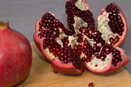 Open frash pomegranate on a wooden desk, pomegranates in the background.の写真素材