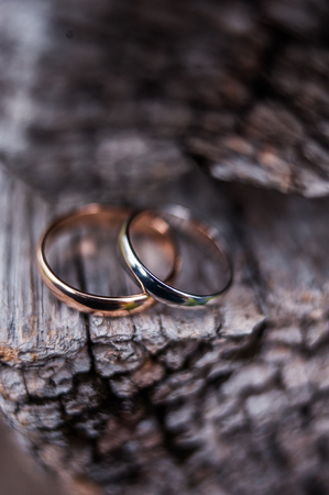 Two wedding rings on a wooden board with cracksの写真素材