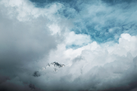 One peak of the mountain can be seen from behind the cloudsの写真素材