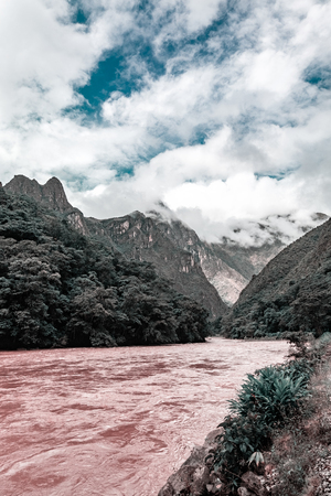 A river flows against a background of a mountain in the cloudsの写真素材