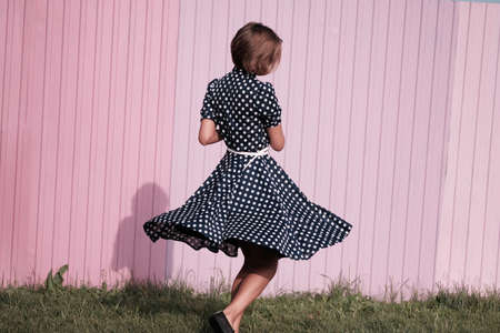 The girl is spinning on the background of a purple wallの写真素材