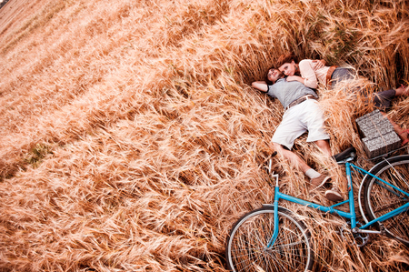 The couple - man,  beautiful girl and bicycle lies on the rye field - view from aboveの写真素材