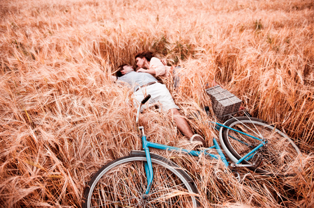 The couple - man,  beautiful girl and bicycle lies on the rye fieldの写真素材