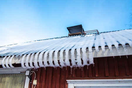 Icicles on the roof of the house a bright winter day.の写真素材