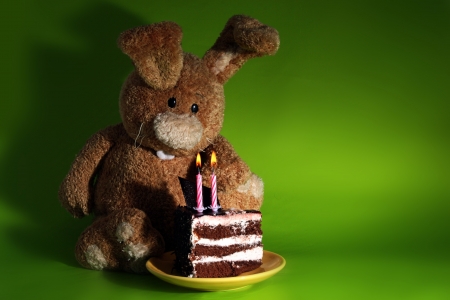 Rabbit toy with cake and candles on greenの写真素材