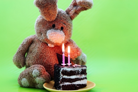 Rabbit toy with cake and candles on greenの写真素材