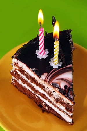 A piece of cake with two candles on greenの写真素材