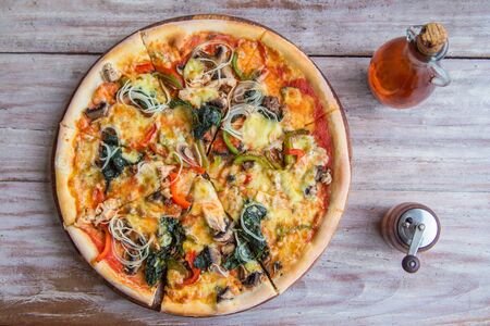Tasty vegetable pizza with mushrooms and herbs, on gray wooden background. Close-up. View from...
