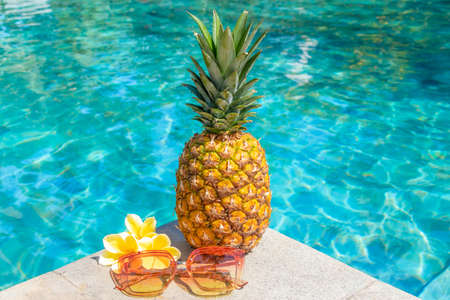 Juicy pineapple and glasses by the pool. Summer concept.