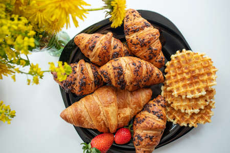 Croissants, waffles and strawberries for breakfast. Delicious desserts close-up.
