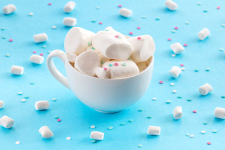 Marshmallow in a white cup of hot chocolate on a blue background.の写真素材