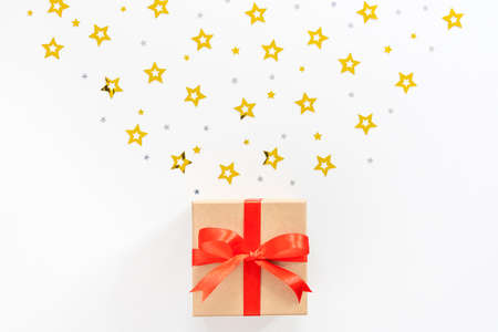 New Years composition. Gift, red ribbon, silvery and golden stars on a white background. Postcard...