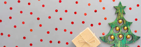 Banner with a Christmas tree, present and red confetti on a gray background. Christmas card. Flat lay, copy space.の写真素材