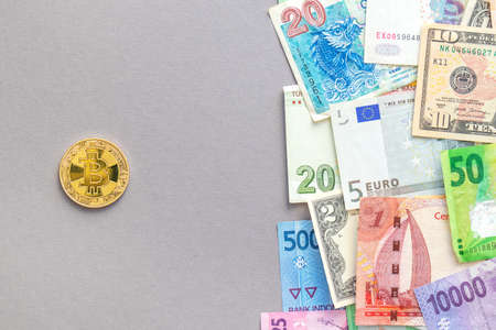 Bitcoin gold coin and paper banknotes of different countries. Concept of international trade, investment and finance.の写真素材