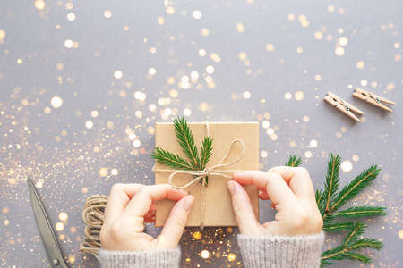 Eco-friendly packaging of christmas gift box, string, fir branch, scissors and wooden trailers on gray background. Zero waste, plastic free. Flat lay, copy space.の写真素材