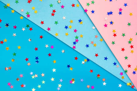Multicolored stars on pastel pink and blue paper. Festive background.の写真素材
