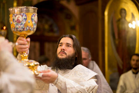 KIEV, UKRAINE - 16 April 2017: The Divine Liturgy at the Kiev Holy Presentation Monastery. Deacon in the altar. Deacon with communion cup for Easter.のeditorial素材