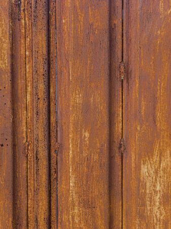 Texture of orange rust on the gate. Illuminated by the orange setting sun.