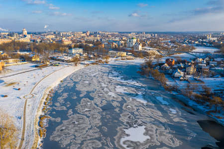 Nice top view of the winter city. Houses and buildings in the snow. Bridge over river. Orthodox churches and a Catholic cathedral. The river is covered with ice.の写真素材