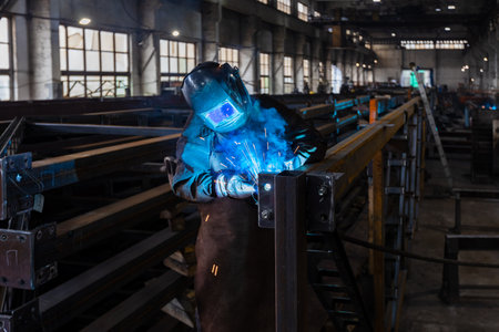 The welder works in the workshop. The moment of welding of metal structures. Beautiful sparks during...