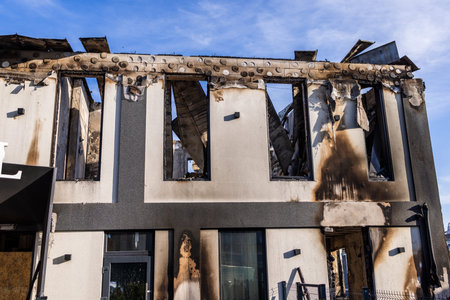 Severely fire damaged building with charred upper floor missing roof sections broken windows and...