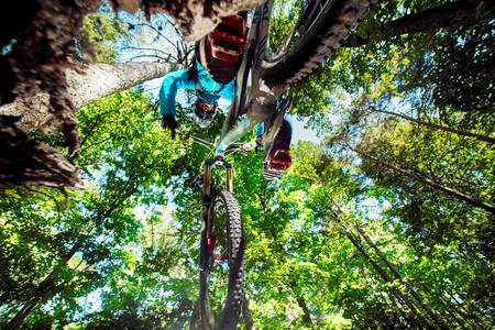 Moscow, Russia - August 18, 2017: Jump and fly on a mountain bike above camera. Rider in action at mountain bike sport. Biker riding in forest. Cool athlete cyclist on a bike. MTB biking.のeditorial素材